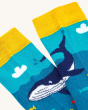 A close up view of the underwater scene on a pair of Frugi Rock My Socks 3-Pack - Deep Water. The image shows two socks creating the whale pattern, with yellow ankle cuffs.