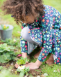 Young girl crouched down planting a flower wearing the Frugi eco-friendly indigo floral print skater dress