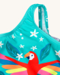 A close up view of the shoulder strap and Macaw on the Frugi Sally Swimsuit - Macaw. A beautiful lined teal blue swimsuit with a colourful macaw, leaf and white flower print, on a cream background.