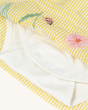 The white body suit inside the Frugi Organic Cotton Devon Baby Body Dress - Flowers, with pop fasteners