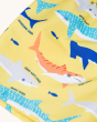 A close up view of the Frugi Boscastle Board Shorts - Banana Sharks, made from recycled bottles. A light banana yellow short with fun and colourful shark print, on a cream background