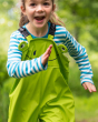 Close up of young girl running wearing the Frugi frog puddle buster trousers