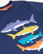 A closer view of the Sharks on the Frugi Avery Applique T-Shirt - Sharks. A deep Navy Blue short sleeve t-shirt made from GOTS organic cotton, with four colourful sharks sewn onto the front. From top to bottom is a lilac whale shark, a yellow great white 