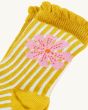 A closer view of the Yellow and White striped frilled socks, with a light pink flower, on a cream background
