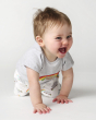 A happy toddler crawling and wearing the Frugi Children's GOTS Organic Cotton Frankie Summer Outfit - Sleepy Sloths.