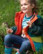 Close up of young girl sat down wearing the Frugi X The National Trust puddle buster waterproof jacket