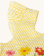 A close up view of the stitching and the yellow and white striped short sleeves on the Frugi Jasmine Dress - Flowers, on a cream background 