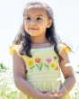 A child happily stood in the sun surrounded by white flowers, whilst wearing the Frugi Jasmine Dress - Flowers made from GOTS Organic cotton. A light sunshine, yellow and white striped short sleeve dress with adjustable ruffle straps, smocked back, and a 