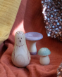 A close up of the wooden bird and two colourful mushrooms from the Grapat Moonlight Tale Play Set, on a colourful fabric background