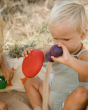 A child playfully pouring sand from the red bowl and purple vase of the Grapat Wooden Rainbow Sorting Pots
