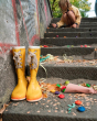 Close up of some Grapat rainbow wooden mandala flower toys scattered next to some yellow wellington boots on some stairs