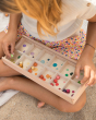 The The Grapat Mis & Match play set being used in a colour matching activity. A child is placing the coloured cubes into the storage box compartments with the same painted, coloured dots.