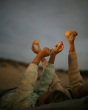 Children lying on their back, holding up the planets in their hands towards the night sky