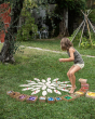 Young girl playing with grapat mandala pieces and the wooden petal platforms on some grass