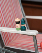 Close up of 2 Grapat kids peg doll toys on the arm of a striped deck chair