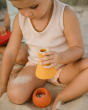 A child is playing with the yellow vase and orange pot from the Grapat Wooden Rainbow Sorting Pots, on the beach