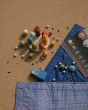 The Grapat Dear Universe Wooden Play Set on a sand background, with a blue blanket. The planets are surrounding a wooden board filled with colourful, rainbow pots