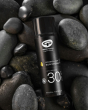 Green People Sports SPF30 Mineral Formula Facial Sun Cream 50ml pictured on a pile of grey polished pebbles 