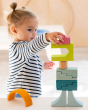 A child concentrating on building a beautiful wooden block stack using the Grimm's Cloud Play set