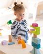 A child concentrating on building a beautiful wooden block stack using the Grimm's Cloud Play set