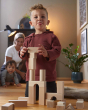 A child placing the HABA Large blocks on top of each other to create a tower, with family in the background