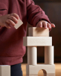 A child carefully placing the Haba Large Building Blocks on top of each other