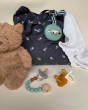 Hevea natural rubber baby dummy and dummy case next to a teddy bear and bag on a beige background