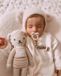 Close up of baby sleeping with a Hevea dummy in their mouth next to a cuddly toy