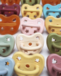 Close up of lots of Hevea natural rubber baby dummies lined up on a white background