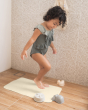 Child stood on a Hevea recycled natural rubber bath mat in a beige shower