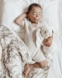 Baby sleeping in a white bed with a Hevea natural rubber pacifier in their mouth