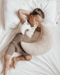 Young boy laying on a white bed with a Hevea natural rubber pacifier in his mouth
