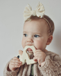 Baby with a bow in their hair holding Hevea Natural Rubber Teether - Kawan the Duck 