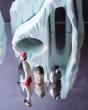 A Holztiger penguin with raised head, and Ostheimer small penguin and a Bumbu penguin chick stood in front of the Bumbu icy cliffs 