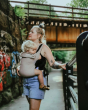 person babywearing on their front using a taupe coloured Integra baby carrier