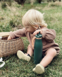 A child happily playing with a wicker basket and sat on the grass. The child is holding the One Green Bottle 500ml Evolution Collection Bottle - Sports Cap in Gecko