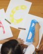 Close up of young child drawing the letters ABC on some paper with the Kitpas rice bran wax coloured crayons