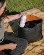 Close up of woman pulling a Klean Kanteen insulated bottle in the salt flats colour out of a black handbag