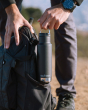Close up of man putting the Klean Kanteen 12oz eco-friendly metal water bottle in the side pocket of a backpack