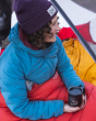 An adult sat inside their tent, holding the Klean Kanteen 12oz Insulated Camping Mug in Mountain Black, with the lid on
