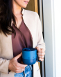 Close up of a woman holding a blue Klean Kanteen insulated steel mug 