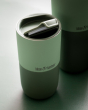Close up of a Klean Kanteen 16oz insulated tumbler with its lid open on a dark green background