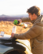 Close up of a man pouring liquid into a Klean kanteen 16oz tkpro stainless steel flask on the bonnet of a car