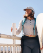 Man leaning on a railing holding a surfboard and a Klean kanteen steel tkpro insulated flask