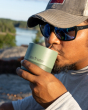 Close up of a man taking a drink from a Klean Kanteen green steel 10oz lowball glass in front of a lake