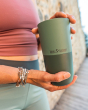 Close up of a woman holding a Klean Kanteen stainless steel tumbler in the Ocean Spray green colour