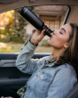 Woman sat in a car drinking from a Klean Kanteen stainless steel drinks bottle with a sports lid