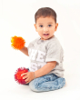 Child kneeling down on a white background holding 2 Lanco natural rubber toy hedgehogs