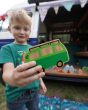 Close up of a boy holding the Lanka Kade lola campervan vehicle toy in front of a blue campervan 
