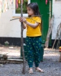 A child playing outside with a large and small stick, wearing a yellow t-shirt and the Little Green Radicals Organic Cotton Little Lizard Comfy Joggers. Made with GOTS Organic Cotton, these joggers are a lovely deep forest green with a playful chameleon l